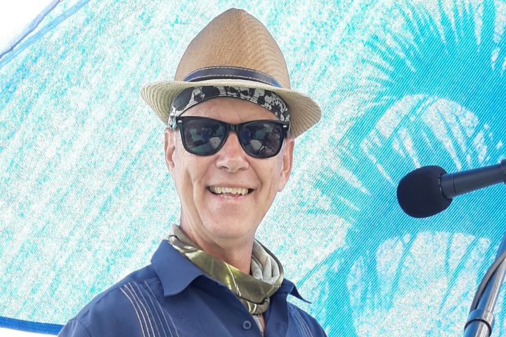 a man wearing a hat and sunglasses posing for the camera